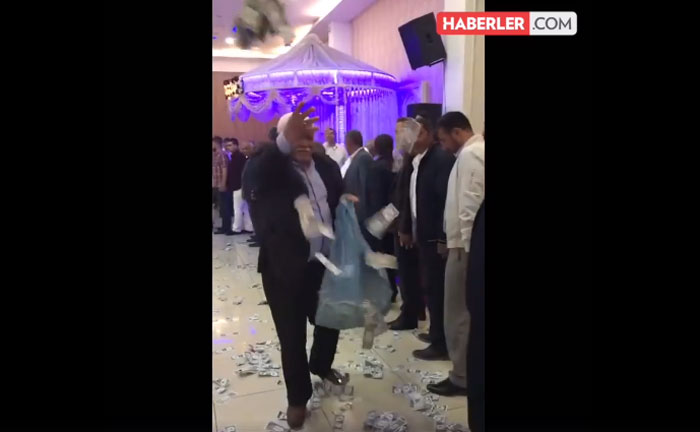 بالفيديو: رجل يرمي الدولارات على الحضور جمعها في كيس قمامة