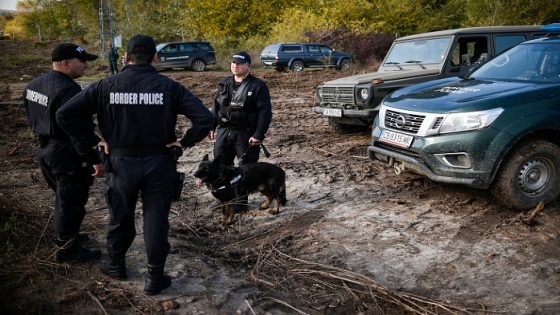 Bulgarian border police personnel stand in position with a dog in front of the border fence on the Bulgaria-Turkey border near the village of Matochina on November 4, 2021. - Bulgaria on November 1, 2021, deployed 350 soldiers to the border with Turkey to help police cope with the growing influx of migrants, the defence minister announced. (Photo by Nikolay DOYCHINOV / AFP) (Photo by NIKOLAY DOYCHINOV/AFP via Getty Images)