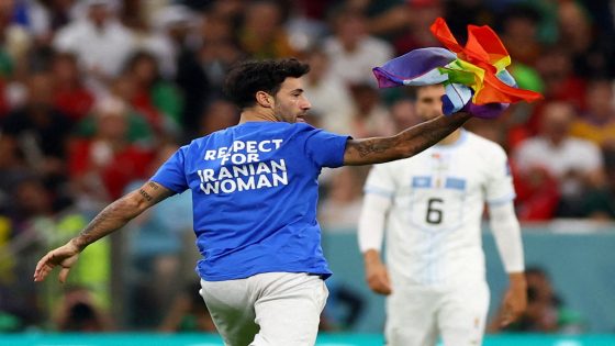 Soccer Football - FIFA World Cup Qatar 2022 - Group H - Portugal v Uruguay - Lusail Stadium, Lusail, Qatar - November 28, 2022 A pitch invader runs onto the pitch wearing a respect for Iranian woman shirt and holds a rainbow colored flag during the match REUTERS/Matthew Childs TPX IMAGES OF THE DAY